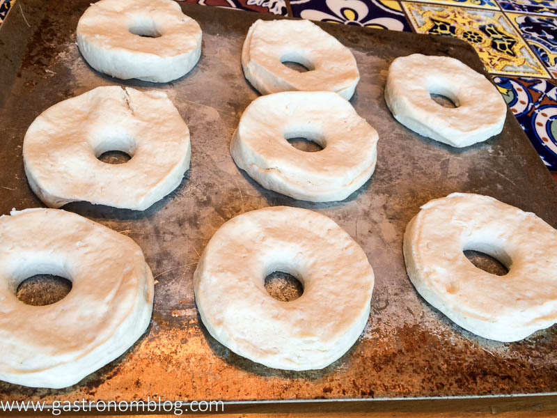 Biscuit dough cut into doughnut shape on a cookie sheet